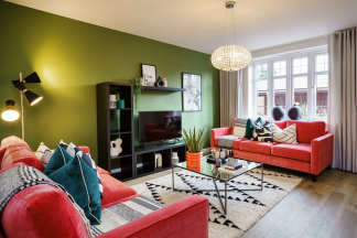A cozy and vibrant living room with a red sofa, patterned rug, and a large window that lets in natural light, creating a warm and inviting atmosphere.