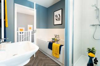 A modern bathroom with a white bathtub, blue walls, and a framed artwork on the wall, along with various decorative elements.