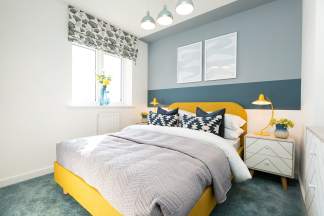 A cozy and vibrant bedroom with a yellow bed frame, patterned curtains, and a mix of gray and blue wall colors, creating a harmonious and inviting atmosphere.