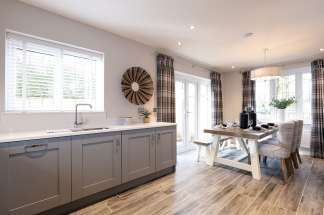 A modern and cozy kitchen with gray cabinets, a wooden dining table, and a large window overlooking a scenic outdoor view.
