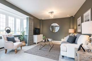 A cozy and well-decorated living room with neutral-toned walls, plush white furniture, and a large circular mirror on the wall, complemented by natural lighting from the windows.