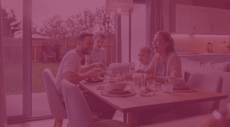 A family enjoys a meal at a dining table in the foreground, with a sunlit backyard visible through a large window in the background.