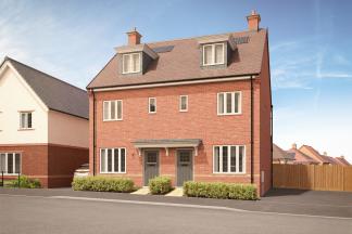 A modern, multi-story brick building with dormer windows and a fenced yard in the foreground, set against a clear blue sky.