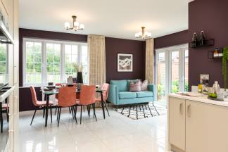 A dining set with coral chairs and a teal sofa are in the foreground, while a kitchen counter and a garden are visible in the background.