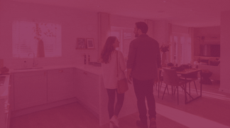 A couple walks through a modern kitchen and dining area.