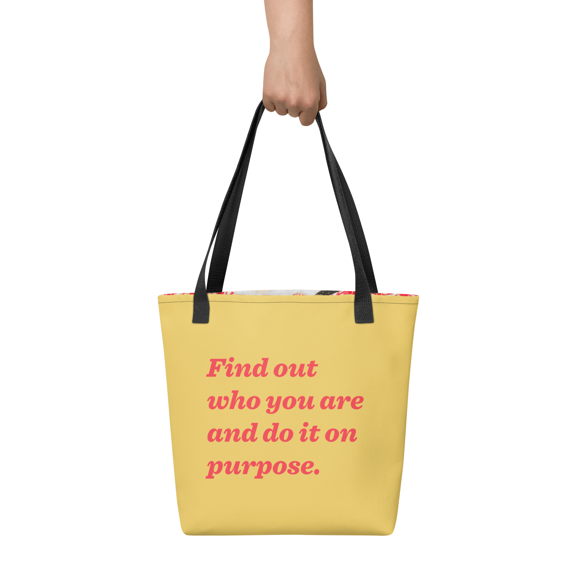 The reverse of the tote held by one hand: butter yellow with “Find out who you are and do it on purpose.” in red