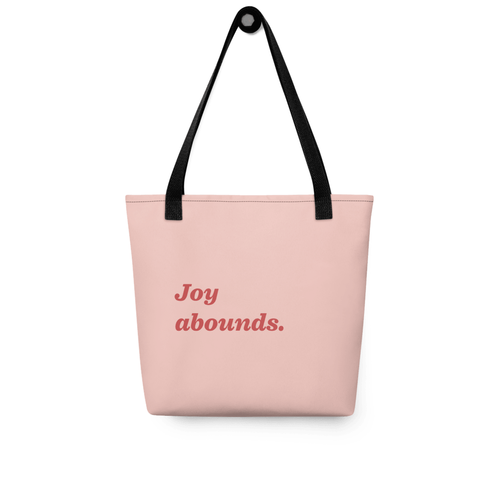 The reverse of the tote: pale pink with “Joy abounds.” in red script