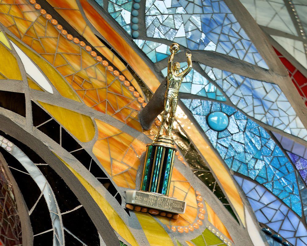 A trophy mounted to a piece of art made from ceramic tile and rocks