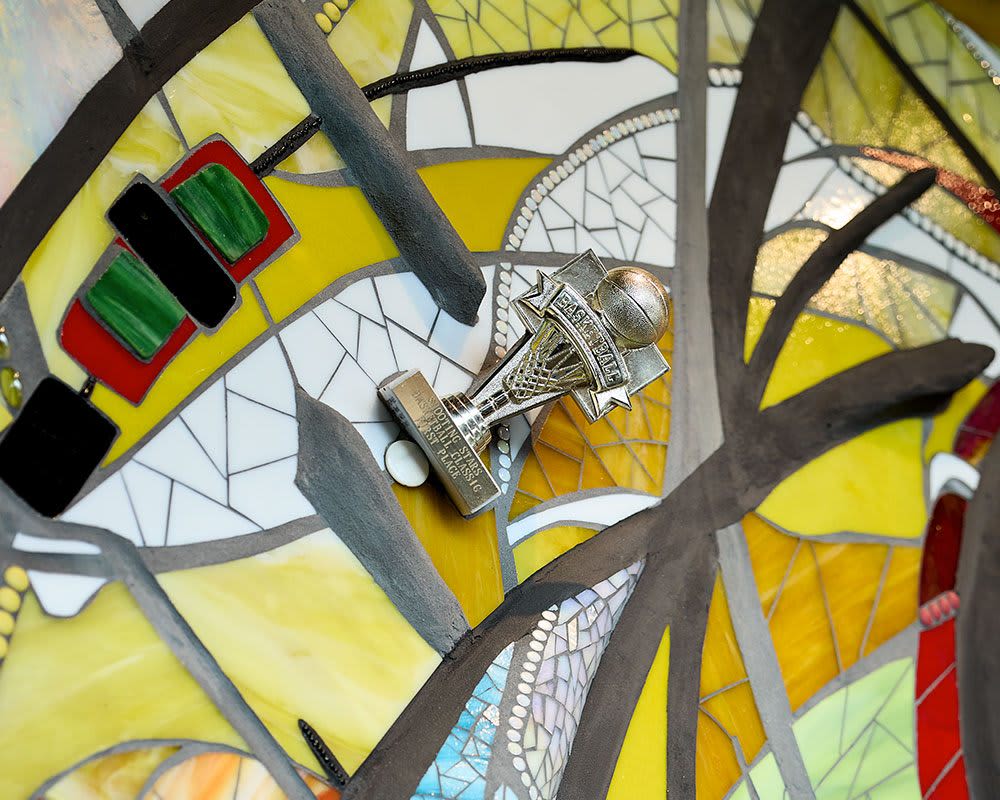A trophy mounted to a piece of art made from ceramic tile and roc