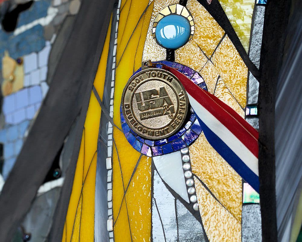 A medal mounted to a piece of art made from ceramic tile and rock