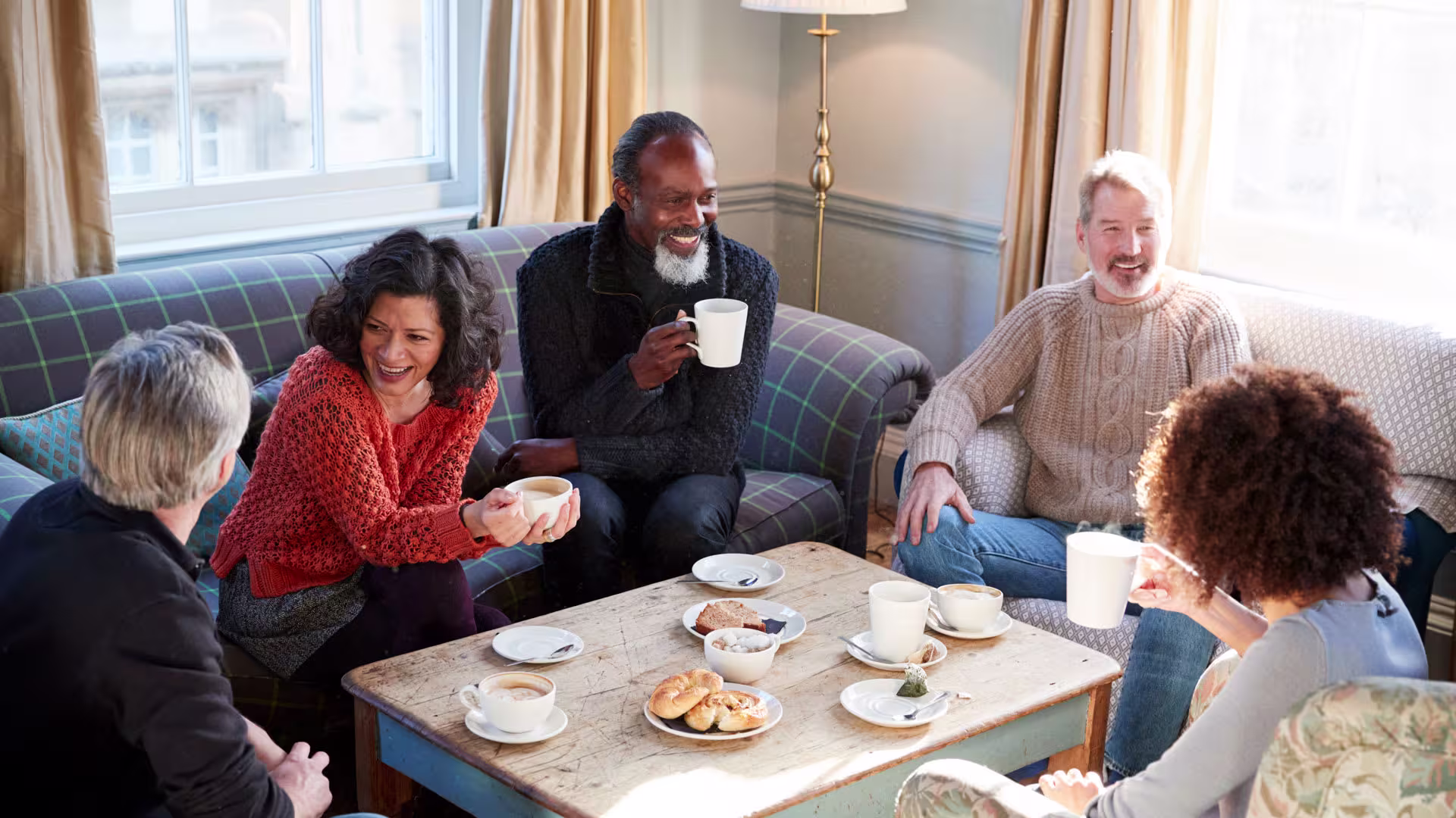 Middle-aged people gathering in a living room for fellowship, coffee and fun Middle-aged people gathering in a living room for fellowship, coffee and fun