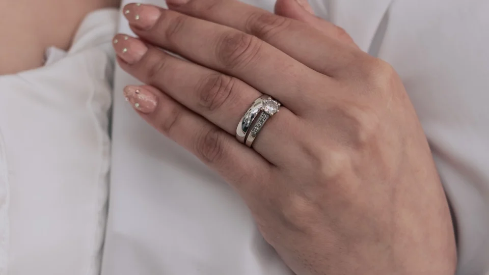 A womans hand wearing a diamond engagement and wedding ring A womans hand wearing a diamond engagement and wedding ring