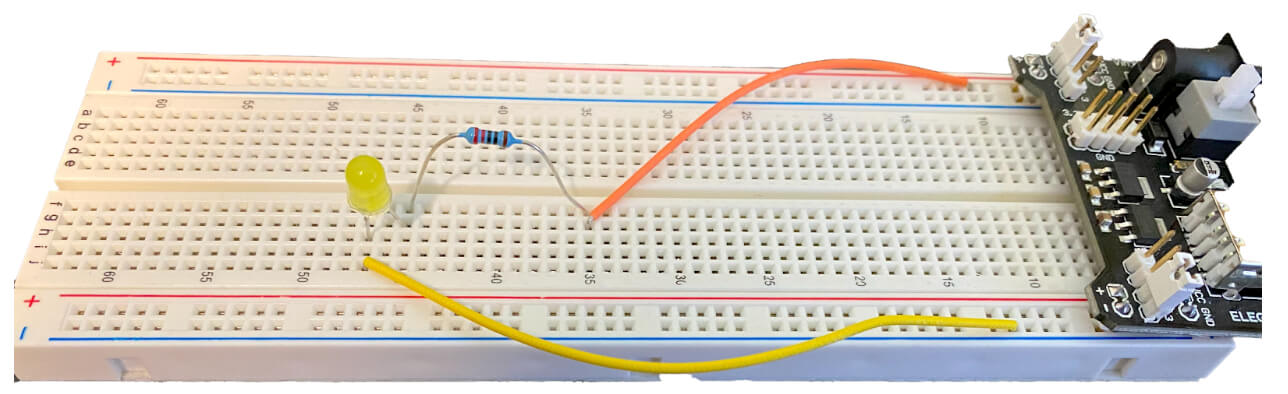 A breadboard has a circuit wired to power rails