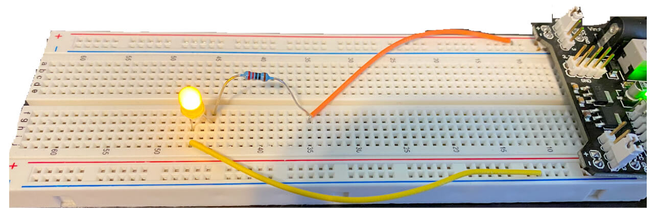 A glowing LED is connected to the breadboard circuit