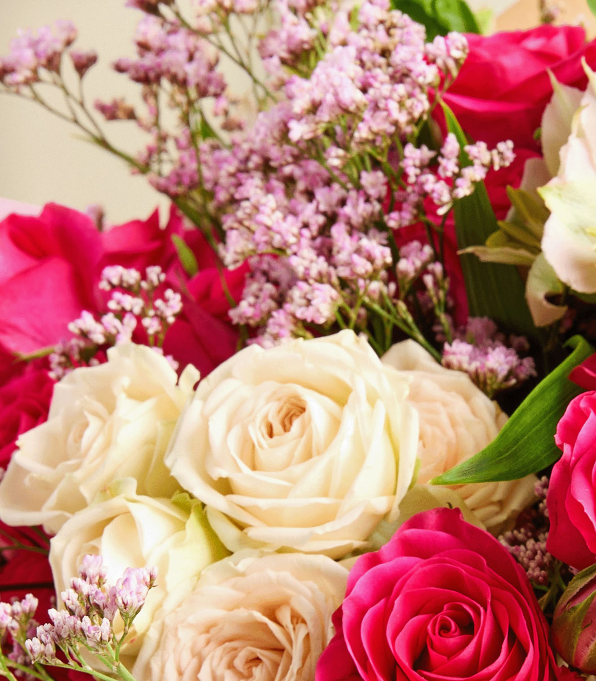 Ein leuchtender Strauß roter und weißer Rosen, begleitet von zarten rosa Blüten, steht im Vordergrund und schafft ein optisch beeindruckendes und harmonisches Arrangement.