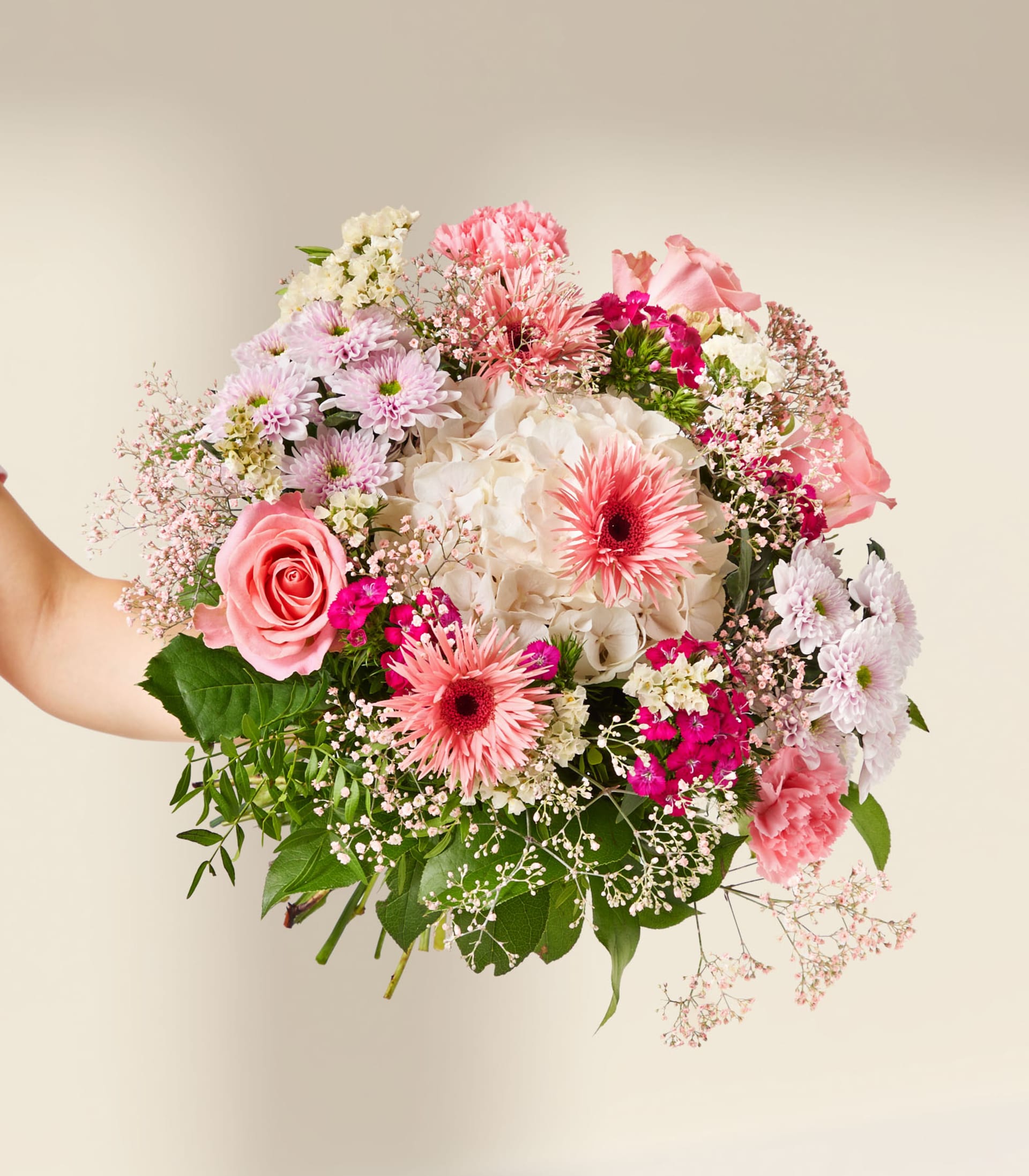 Eine Hand hält einen leuchtenden Strauß rosa und weißer Blumen vor einem sanften, neutralen Hintergrund.