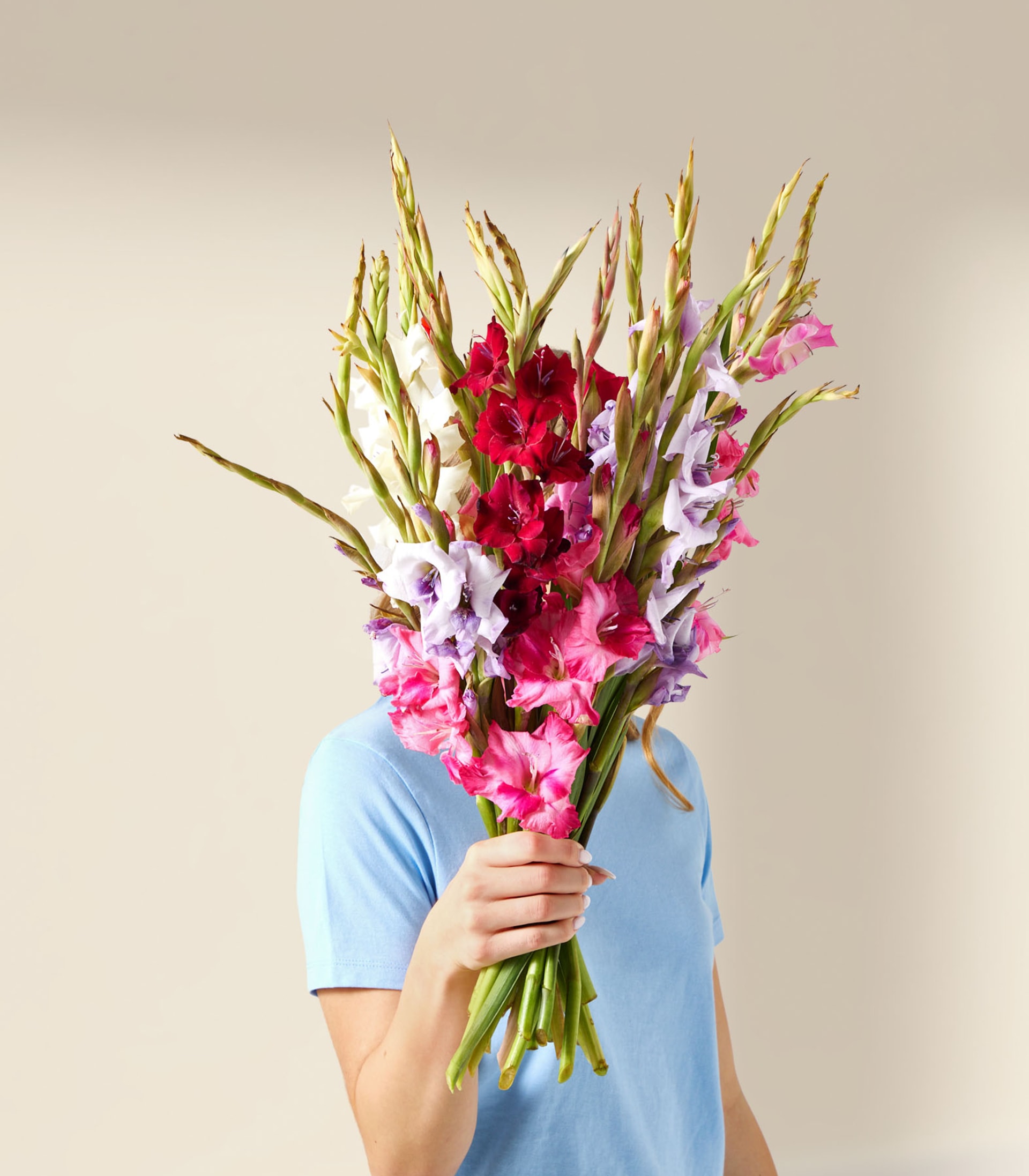 Ein lebendiger Strauß rosa und weißer Blumen, darunter Gladiolen und Lilien, füllt den Rahmen mit seinen üppigen, bunten Blütenblättern vor einem weichen, unscharfen Hintergrund.