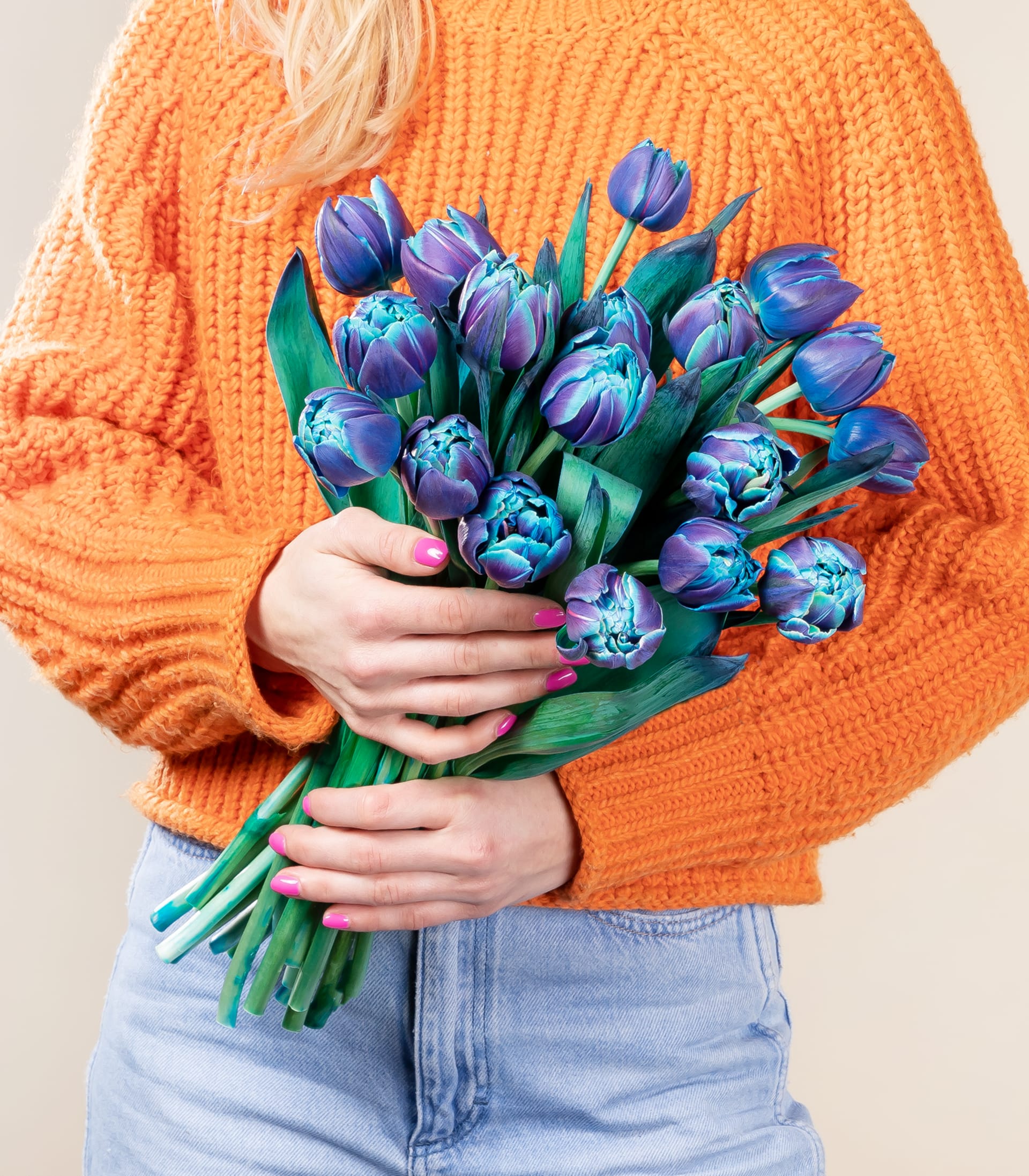 Ein lebendiger Strauß üppiger, violett-blauer, artischockenartiger Blüten vor einem weichen, neutralen Hintergrund.