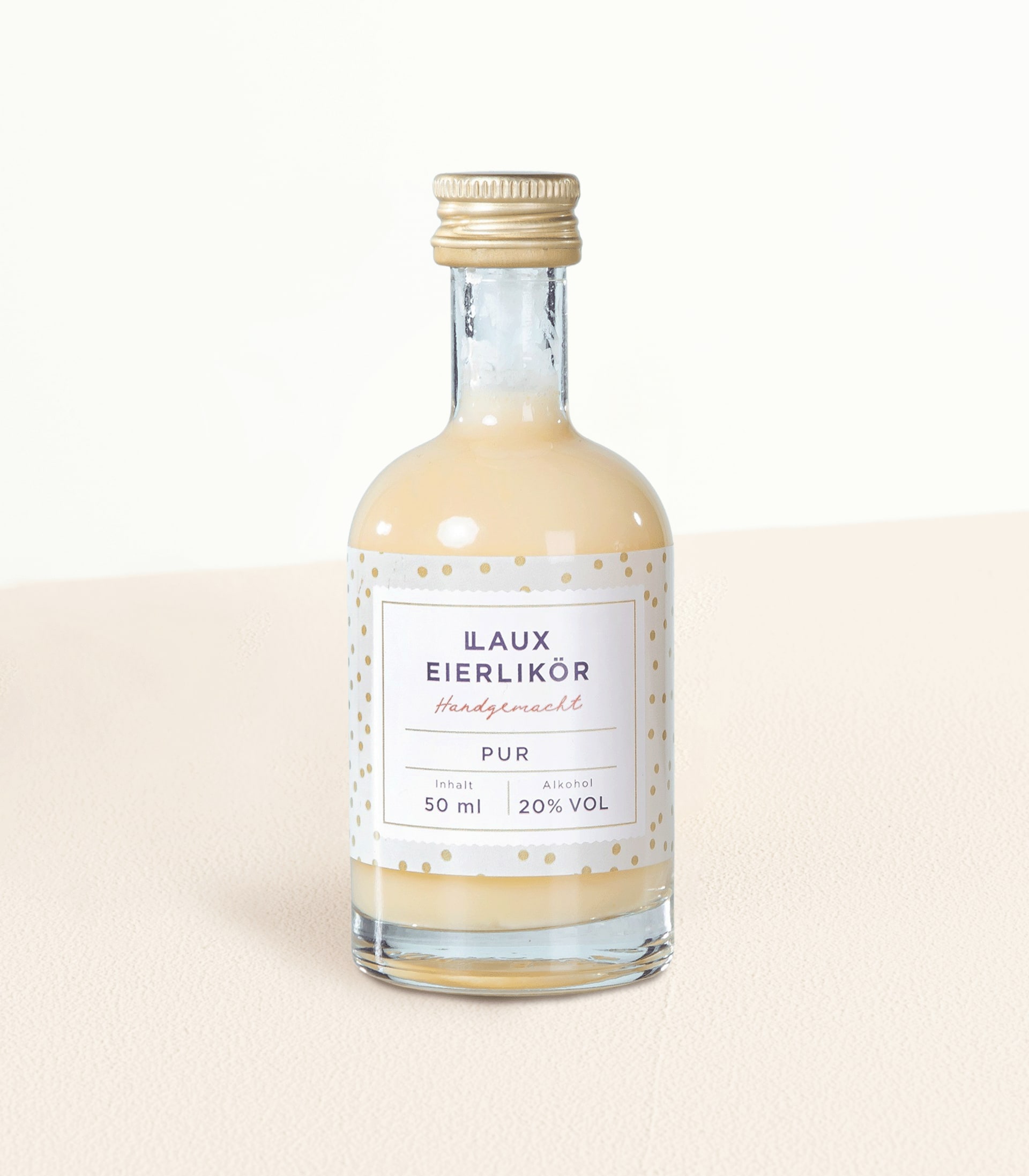 Eine Glasflasche Ilaux Eierlikör, ein deutscher Eierlikör, steht auf einer hellen Oberfläche vor einem schlichten Hintergrund.
