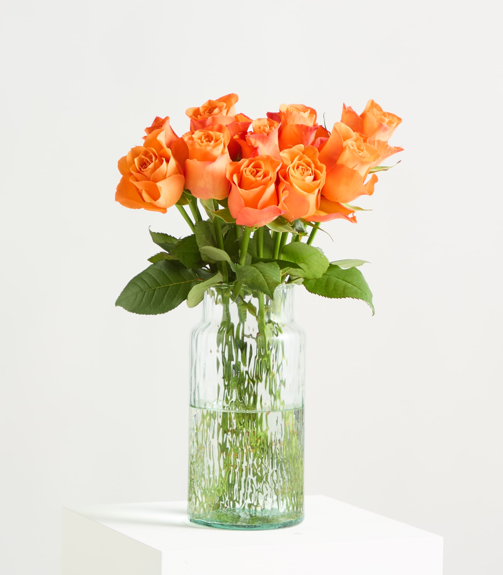 Leuchtend orangefarbene Rosen mit üppigen Blütenblättern und grünen Blättern füllen den Rahmen und ergeben ein auffälliges und optisch ansprechendes Blumenarrangement.