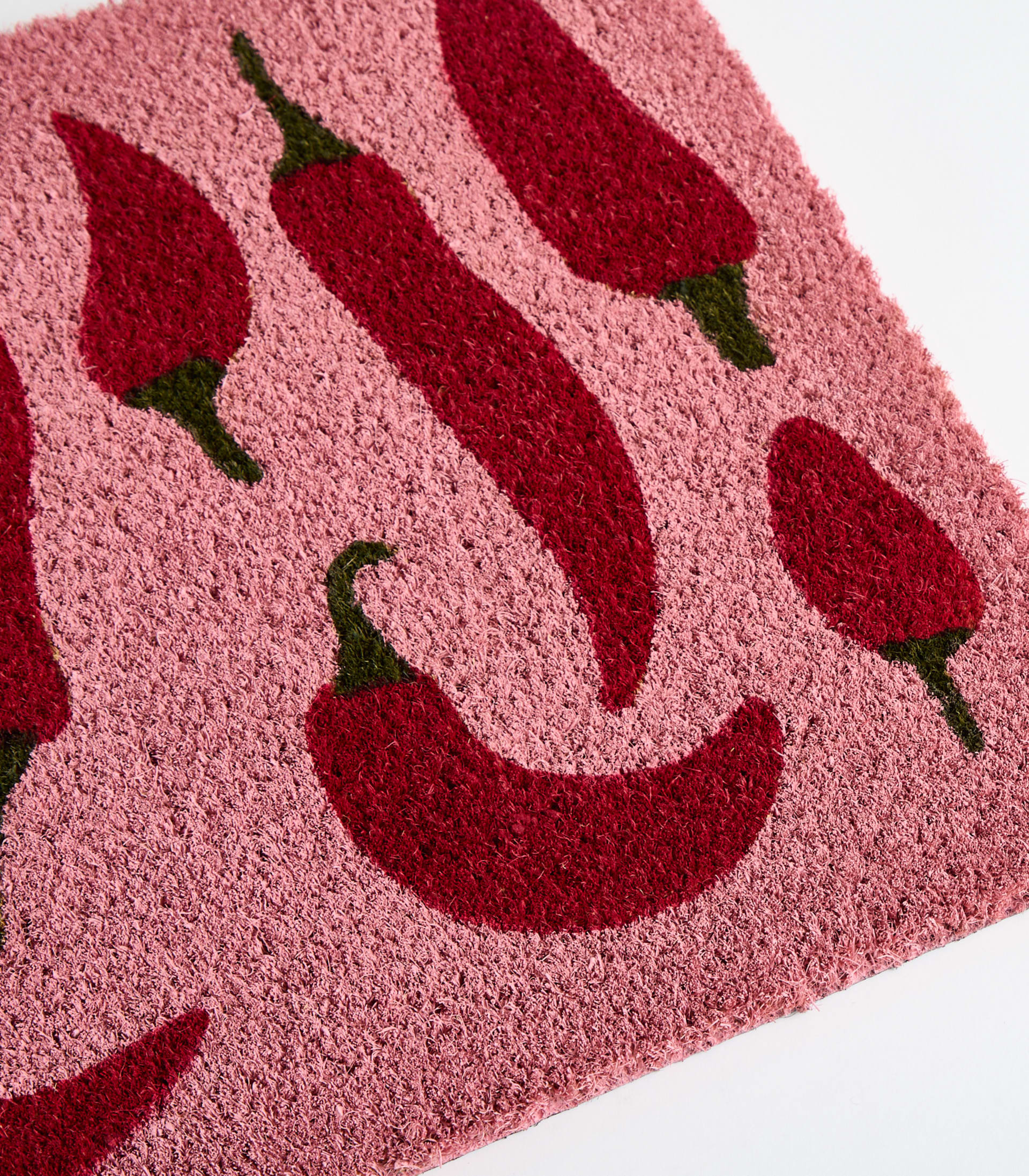 Das Bild zeigt einen rosa Hintergrund, auf dem verschiedene rote Chilischoten verstreut sind.