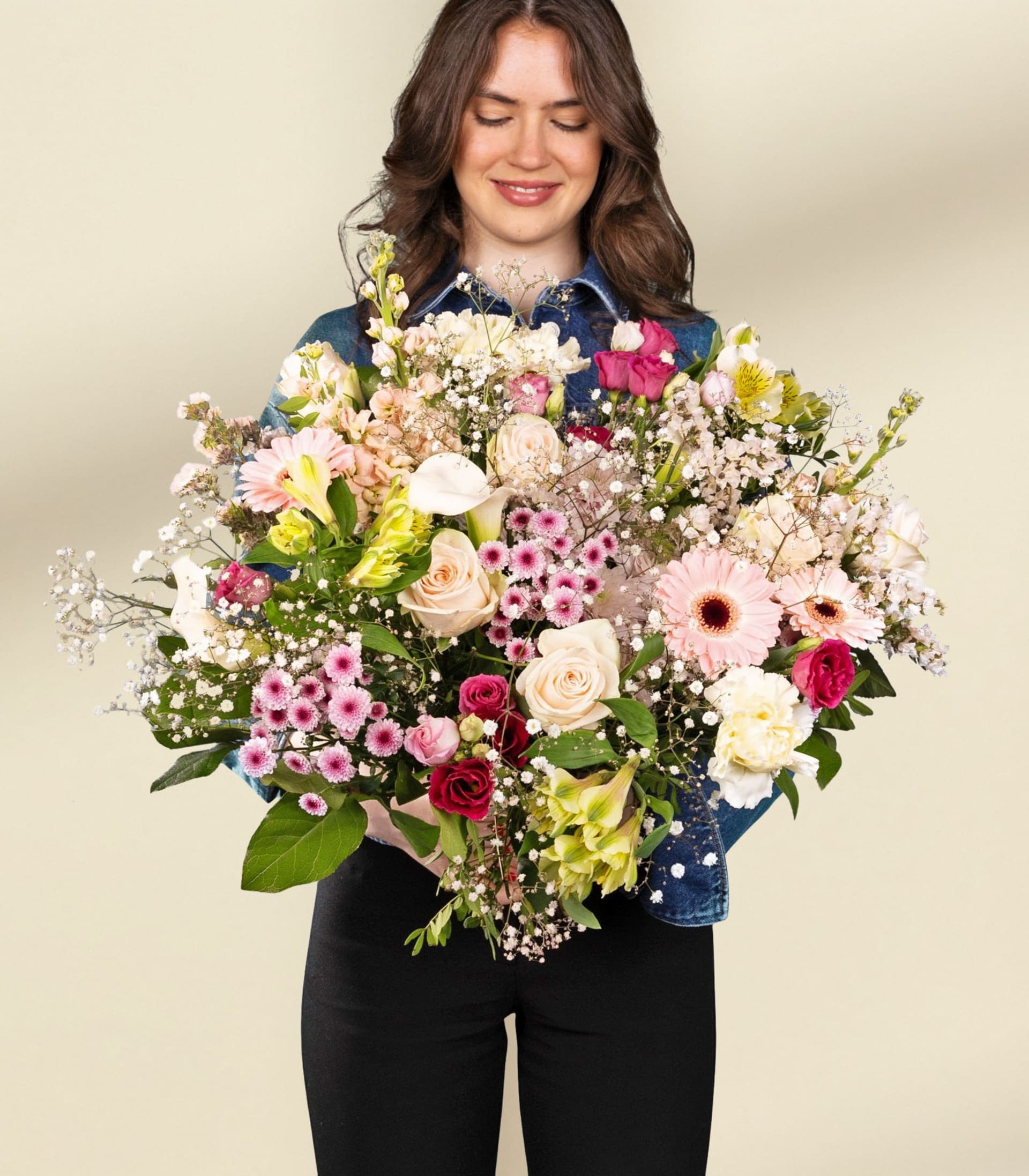 Ein lebendiger Strauß verschiedener Blumen, darunter rosa Gerbera, weiße Rosen und zartes Schleierkraut, vor einem sanften blauen Hintergrund.