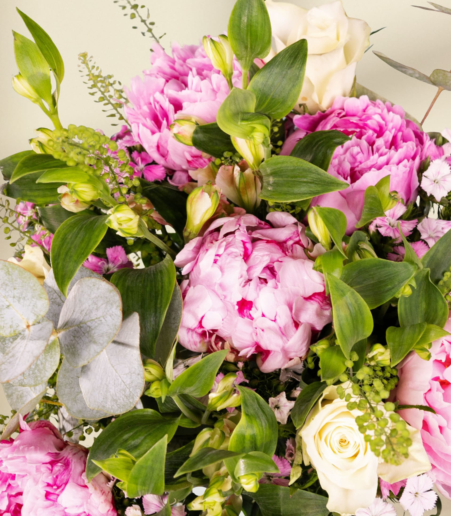 Ein leuchtender Strauß aus rosa Pfingstrosen, weißen Blumen und Grünpflanzen wird in den Händen einer Person gehalten, die vor einem schlichten Hintergrund einen blauen Anzug trägt.