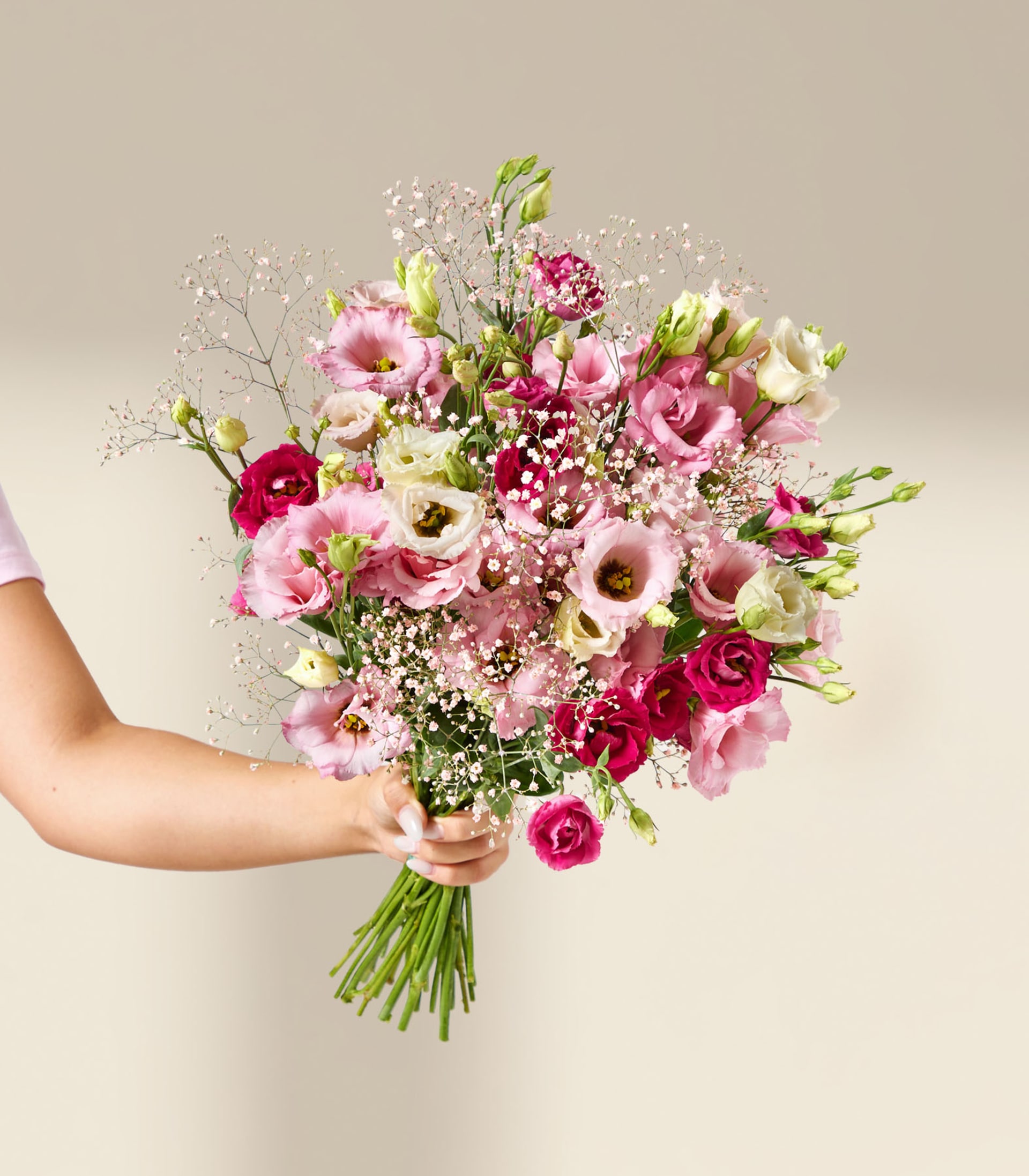 Ein lebendiger Strauß rosa und violetter Blumen, darunter Rosen und Schleierkraut, vor einem sanften grauen Hintergrund.