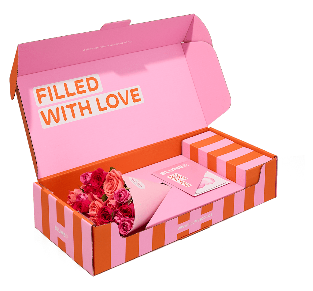 In einer rosa-orange gestreiften Schachtel befindet sich ein Strauß rosa und roter Rosen. Auf der Innenseite des Deckels ist vor weißem Hintergrund der Schriftzug „FILLED WITH LOVE“ aufgedruckt. (Beschreibungstext KI-generiert)