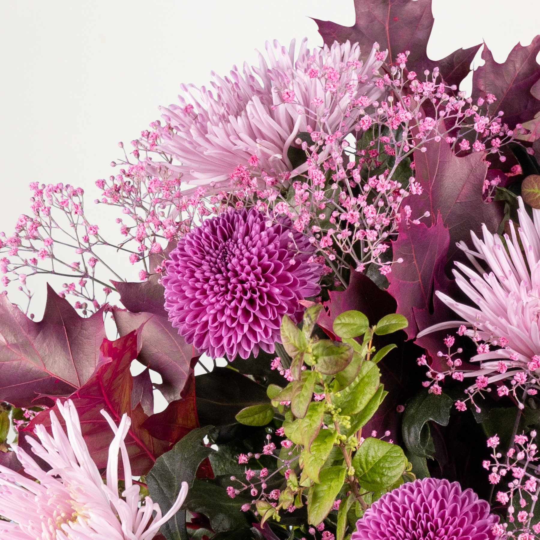 Ein lebendiger Strauß üppiger, rosa Chrysanthemen und anderer zarter Blumen vor neutralem Hintergrund.