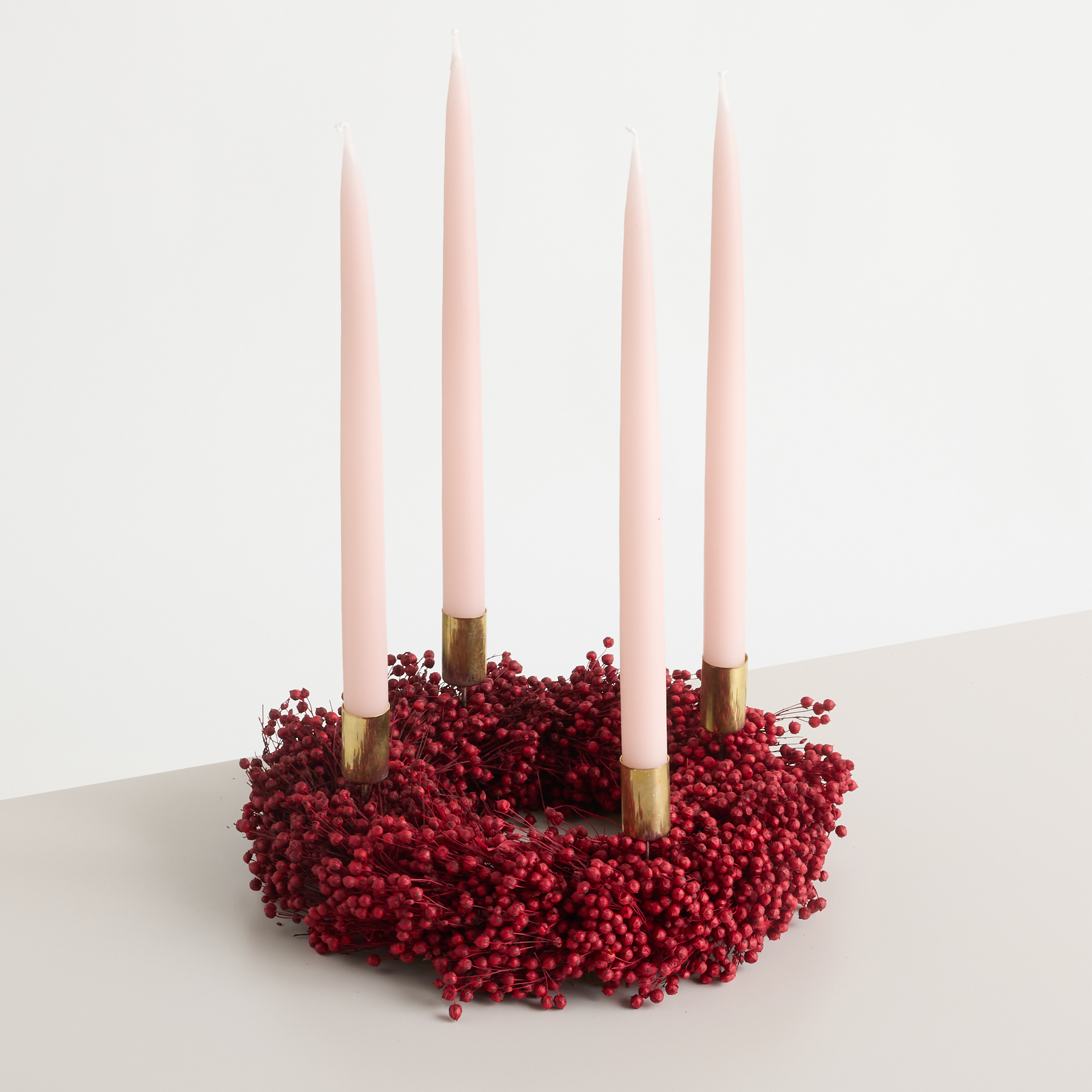 Auf einem schlichten weißen Hintergrund liegt ein rosafarbenes, ringförmiges Gebäck, das mit roten Streuseln bedeckt ist, zusammen mit einigen rosafarbenen Stäbchen.