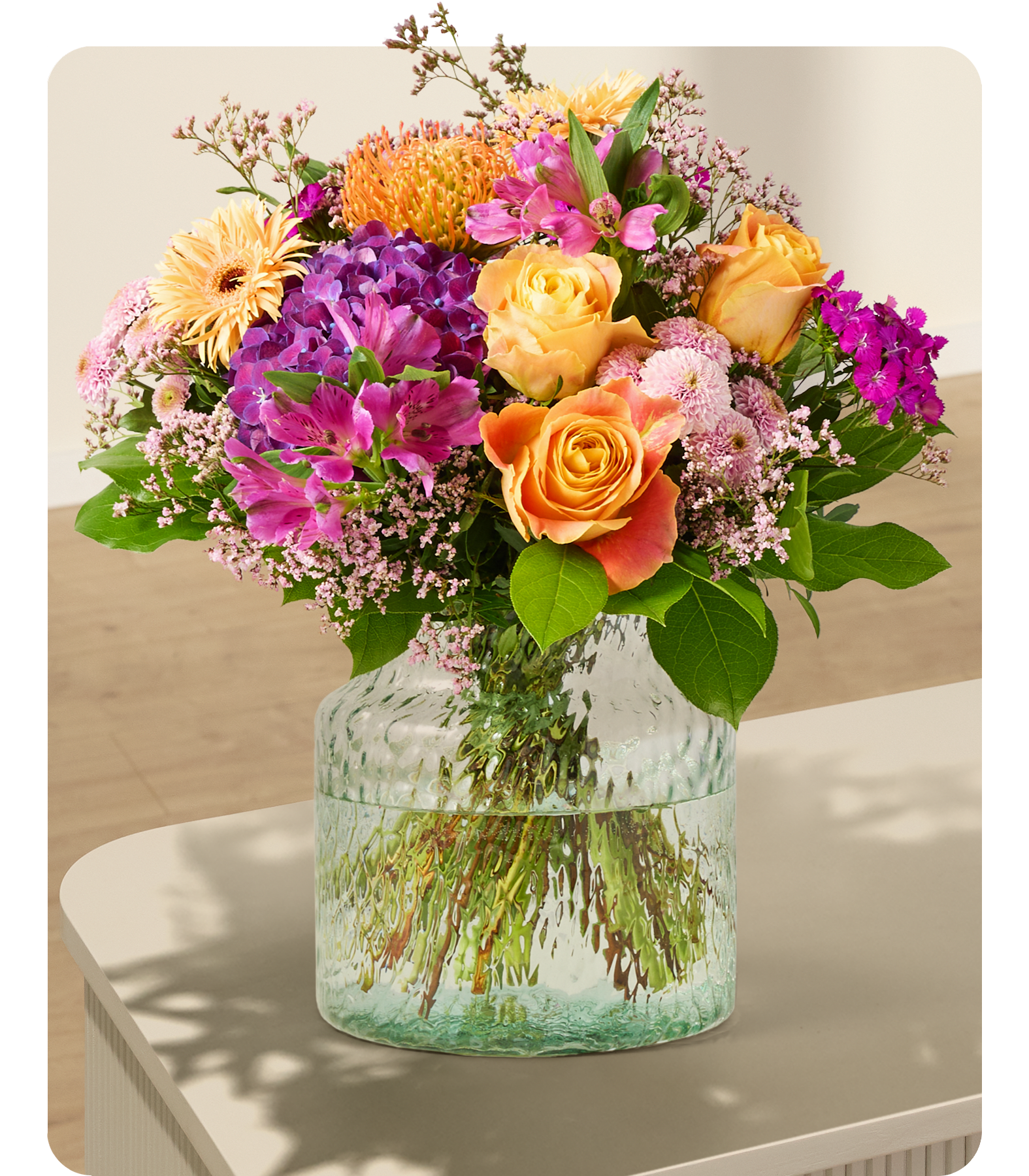 Ein lebendiger Strauß bunter Blumen, darunter Sonnenblumen, Rosen und Hortensien, wunderschön arrangiert vor einem schlichten weißen Hintergrund.