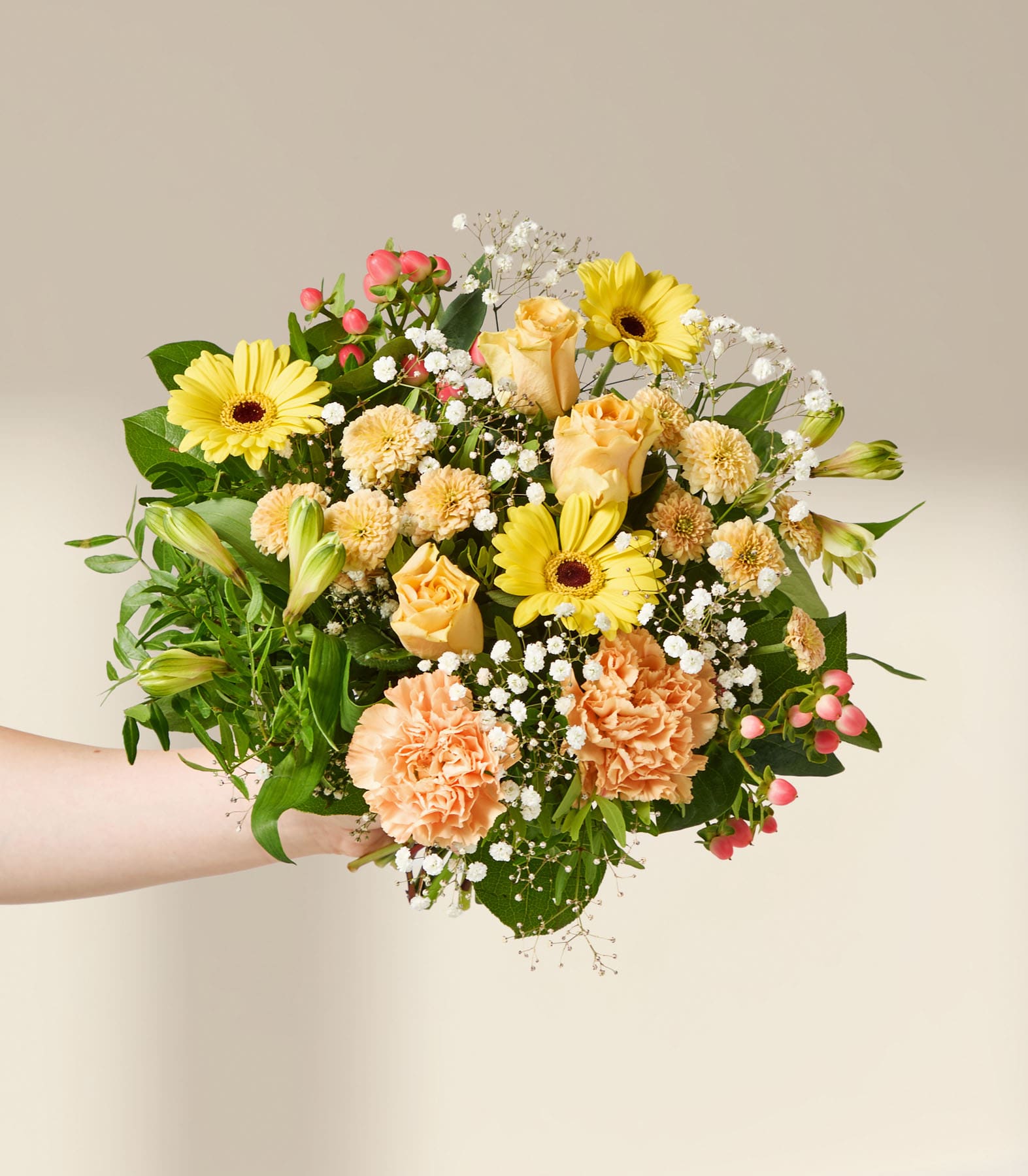 Eine Hand hält einen leuchtenden Strauß gelber und orangefarbener Blumen, akzentuiert mit zartem weißen Schleierkraut, vor einem sanften, neutralen Hintergrund.