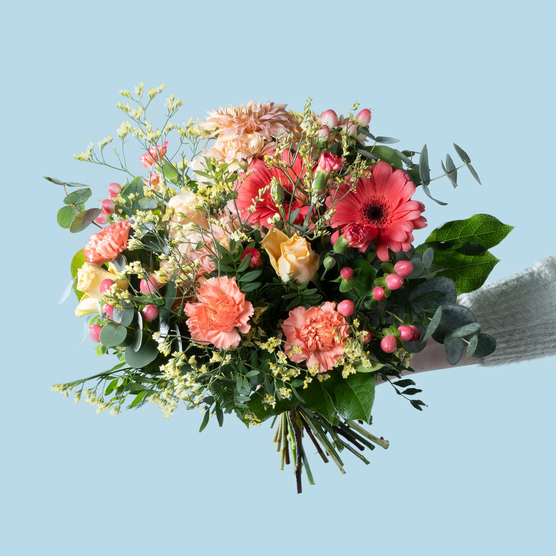 Ein lebendiger Strauß bunter Blumen, darunter Gerbera, Rosen und andere Blüten, steht vor dem Hintergrund eines ruhigen blauen Himmels.