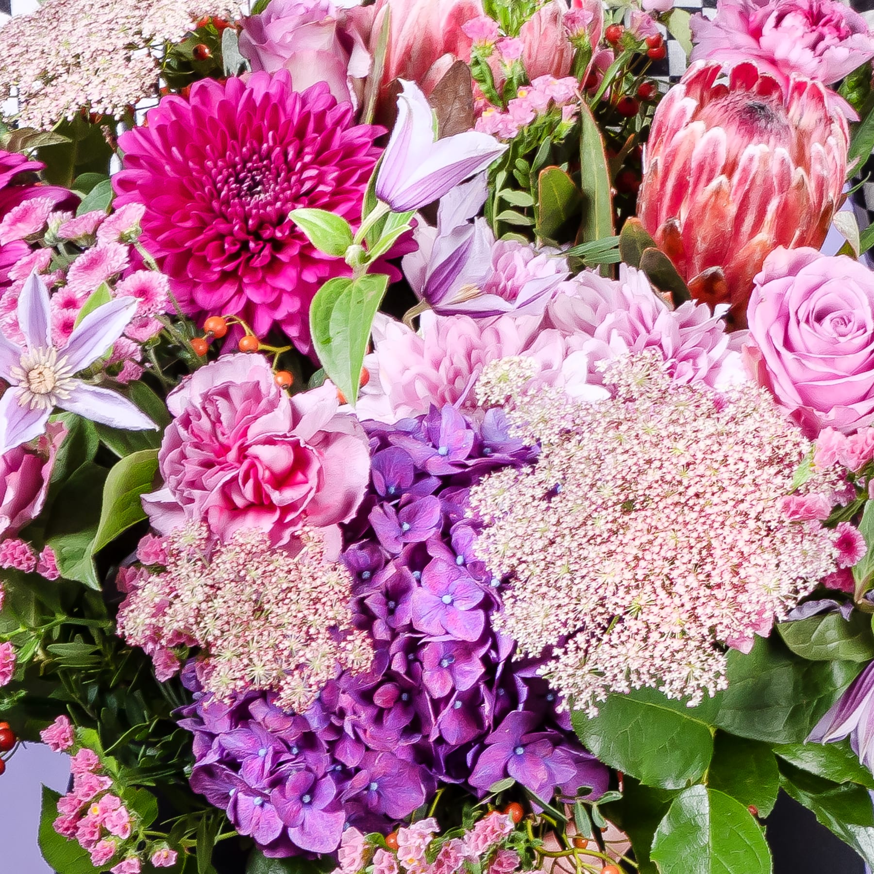 Ein leuchtender Strauß verschiedener rosa, violetter und weißer Blumen, darunter Rosen, Dahlien und Hortensien, füllt den Rahmen mit einer üppigen und farbenfrohen Pracht.