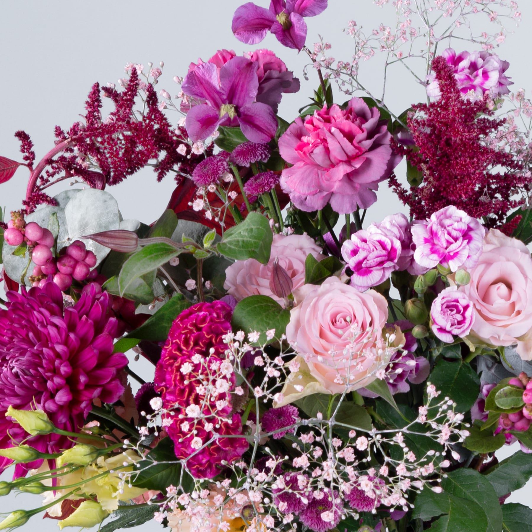 Ein lebendiger Strauß verschiedener rosa und violetter Blumen, darunter Rosen, Dahlien und andere Blüten, vor einem hellen Hintergrund.