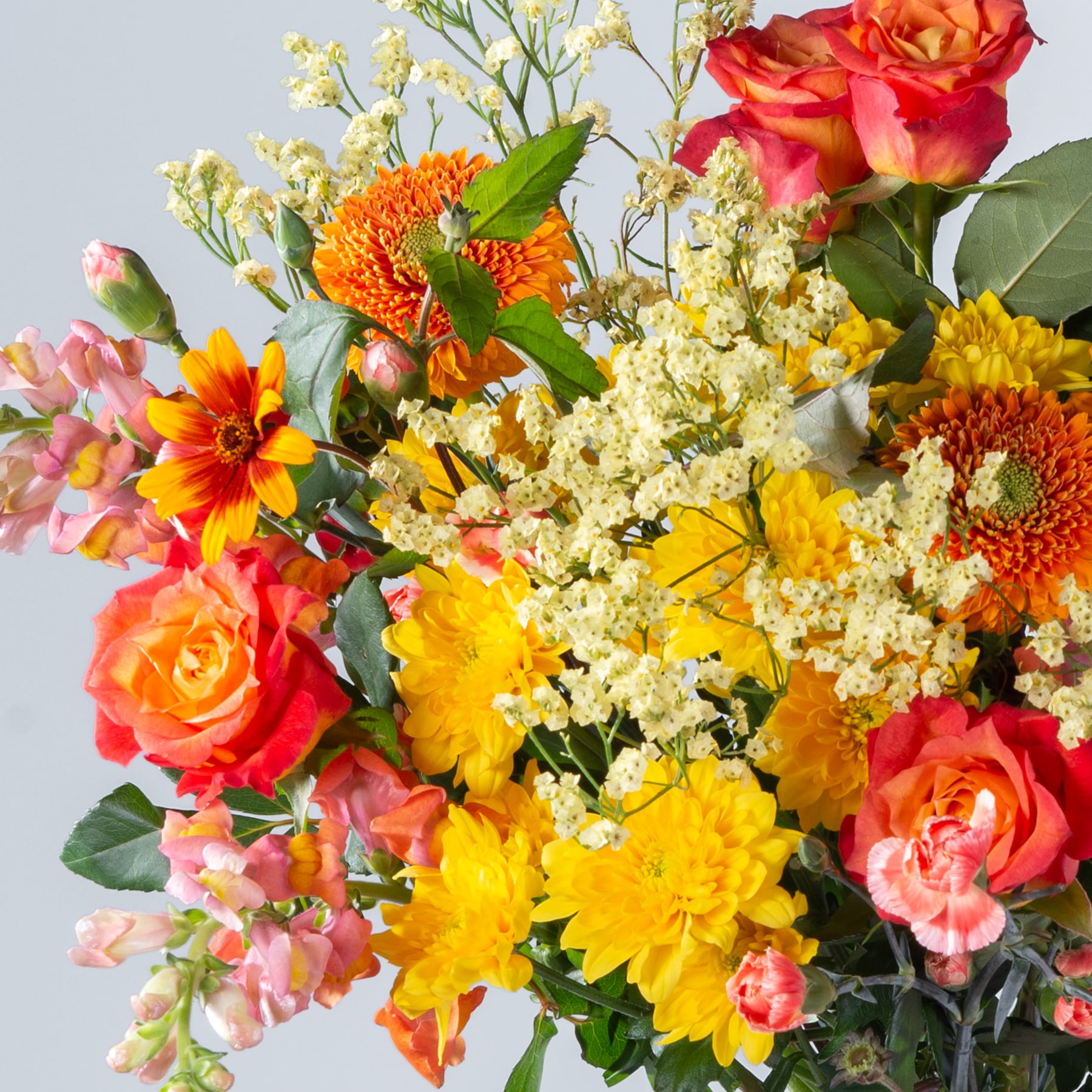 Ein lebendiger Strauß bunter Blumen, darunter Rosen, Gänseblümchen und Chrysanthemen, vor einem schlichten Hintergrund.