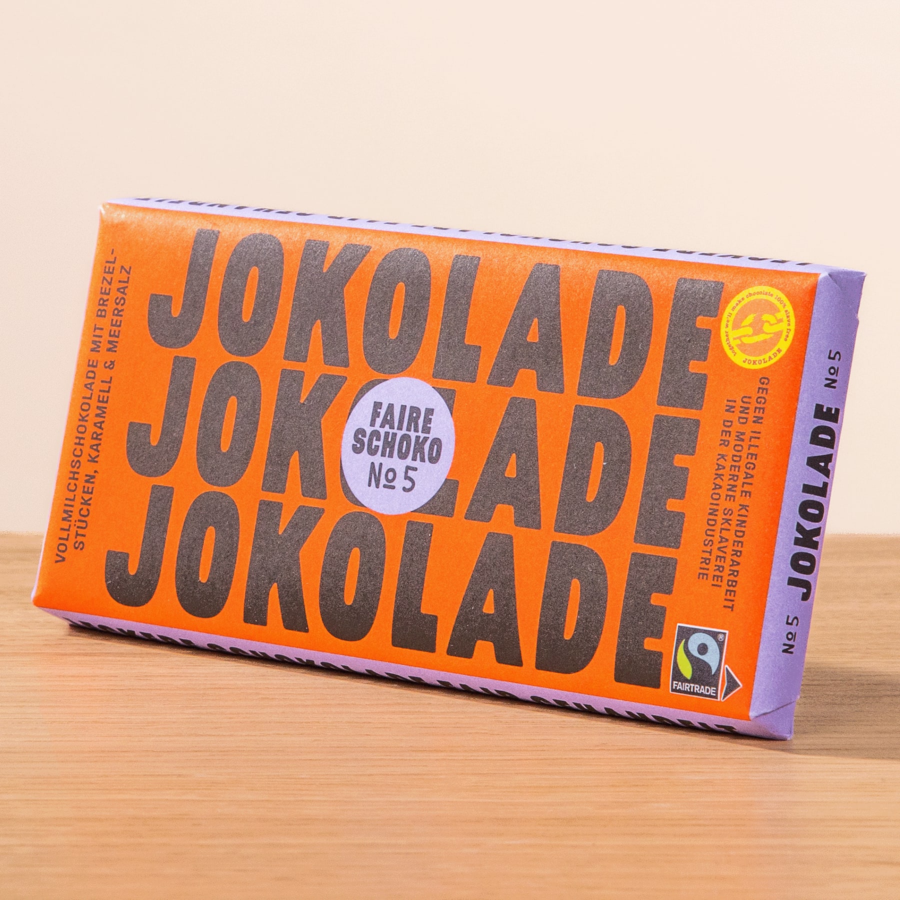 Eine leuchtend orangefarbene Schokoriegelpackung mit dem deutlich sichtbaren Text „JOKOLADE JOKOLADE JOKOLADE“ vor einem schlichten Hintergrund.