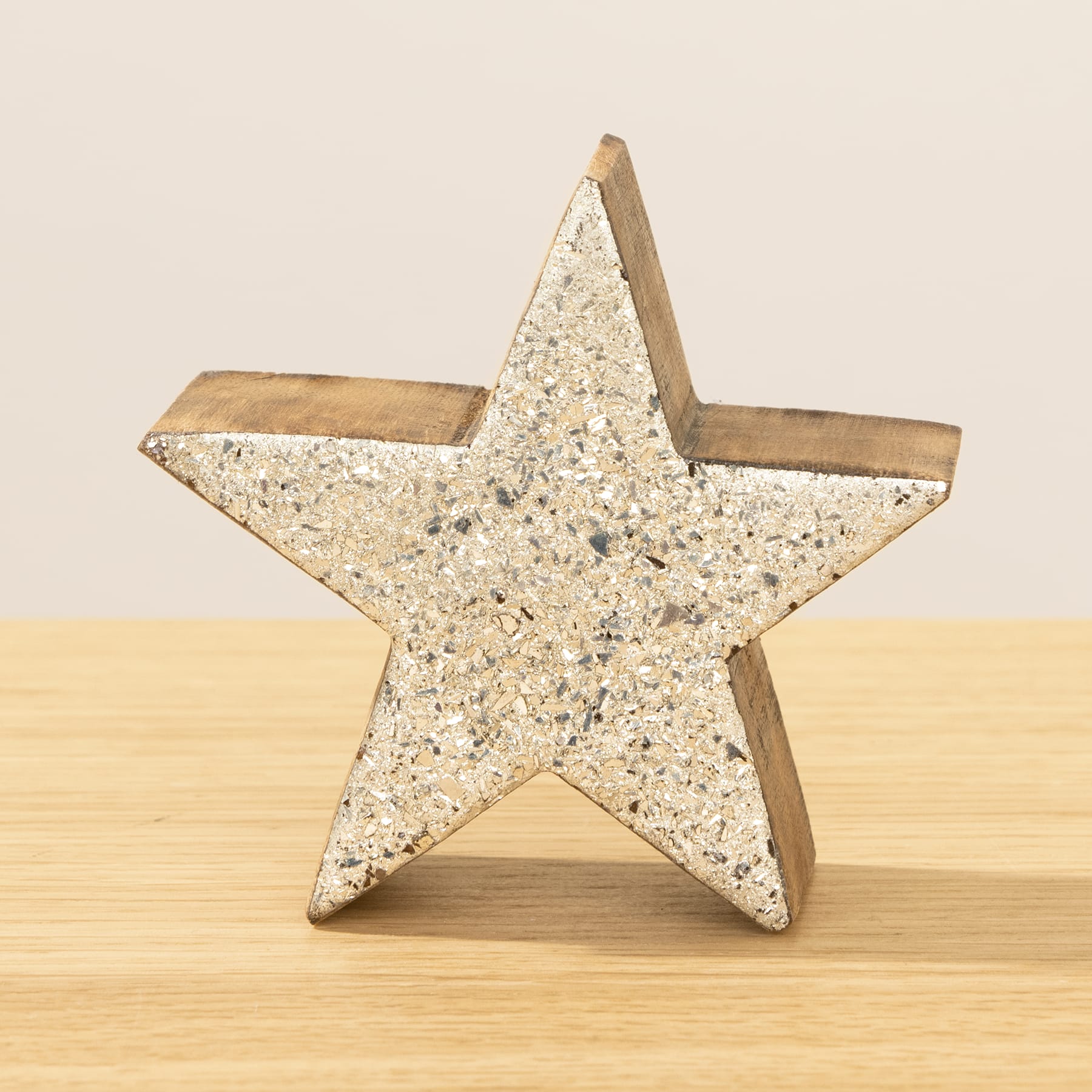Ein sternförmiges Holzobjekt mit einer granitähnlichen Oberfläche steht auf einem Holztisch vor einem schlichten Hintergrund.