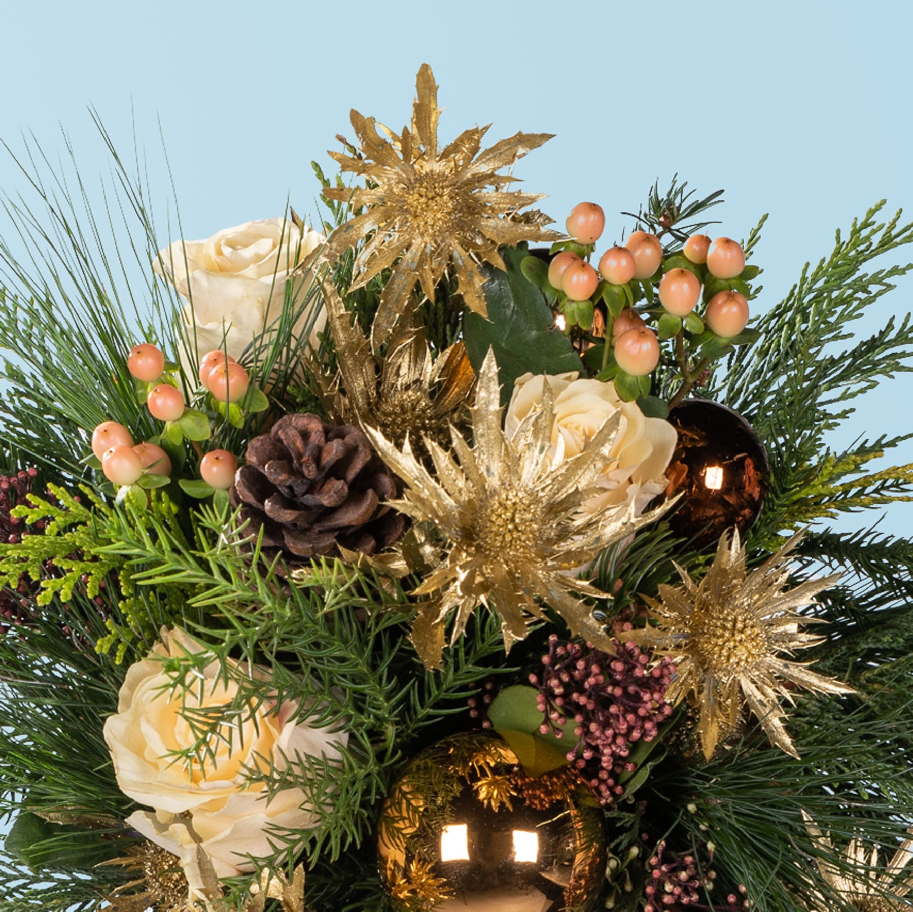 Ein leuchtender Strauß goldener Blumen, Tannenzweige und Beeren vor einem klaren blauen Himmel, der ein festliches und von der Natur inspiriertes Arrangement ergibt.