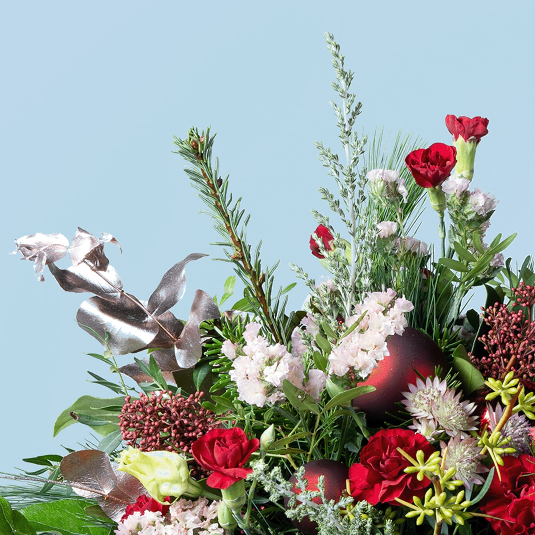 Ein farbenfroher Strauß verschiedener Blumen, darunter rote Rosen, weiße Nelken und gelbe Gänseblümchen, vor dem Hintergrund eines klaren blauen Himmels.