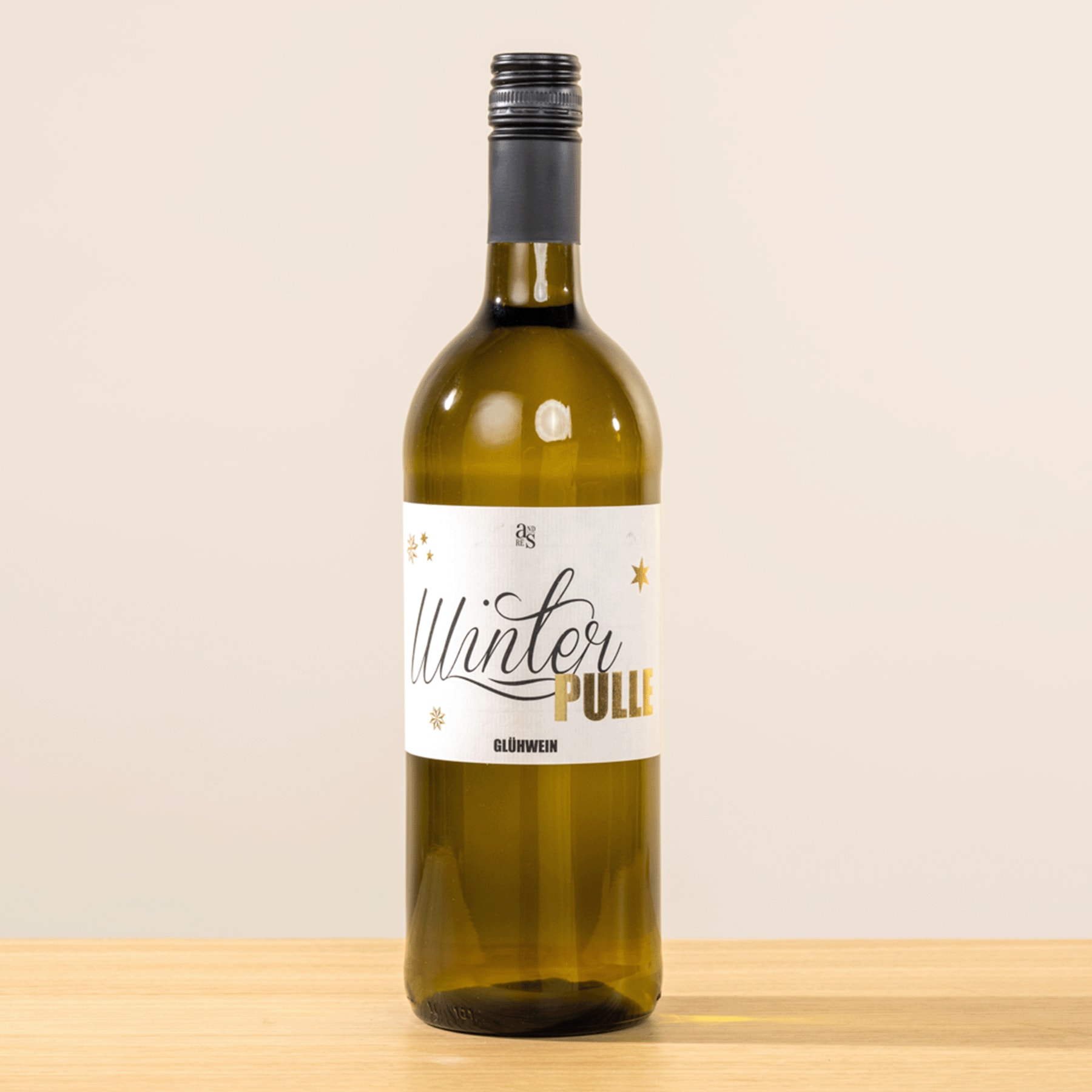Eine Flasche Weißwein mit der Aufschrift „Winter Pull“ steht auf einer Holzoberfläche vor einem schlichten beigen Hintergrund.