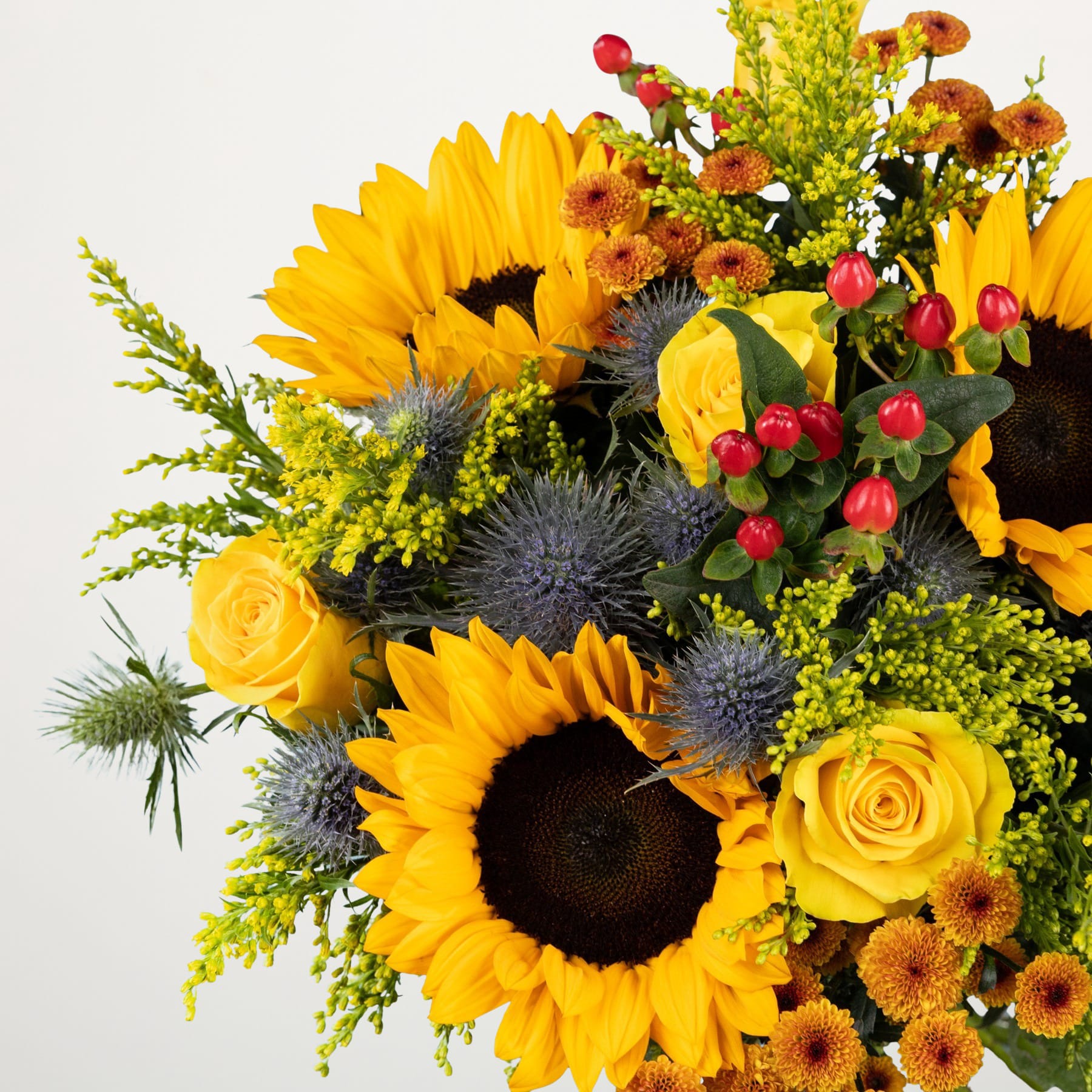 Ein lebendiger Strauß aus Sonnenblumen, Rosen und anderen bunten Blumen vor einem schlichten weißen Hintergrund.