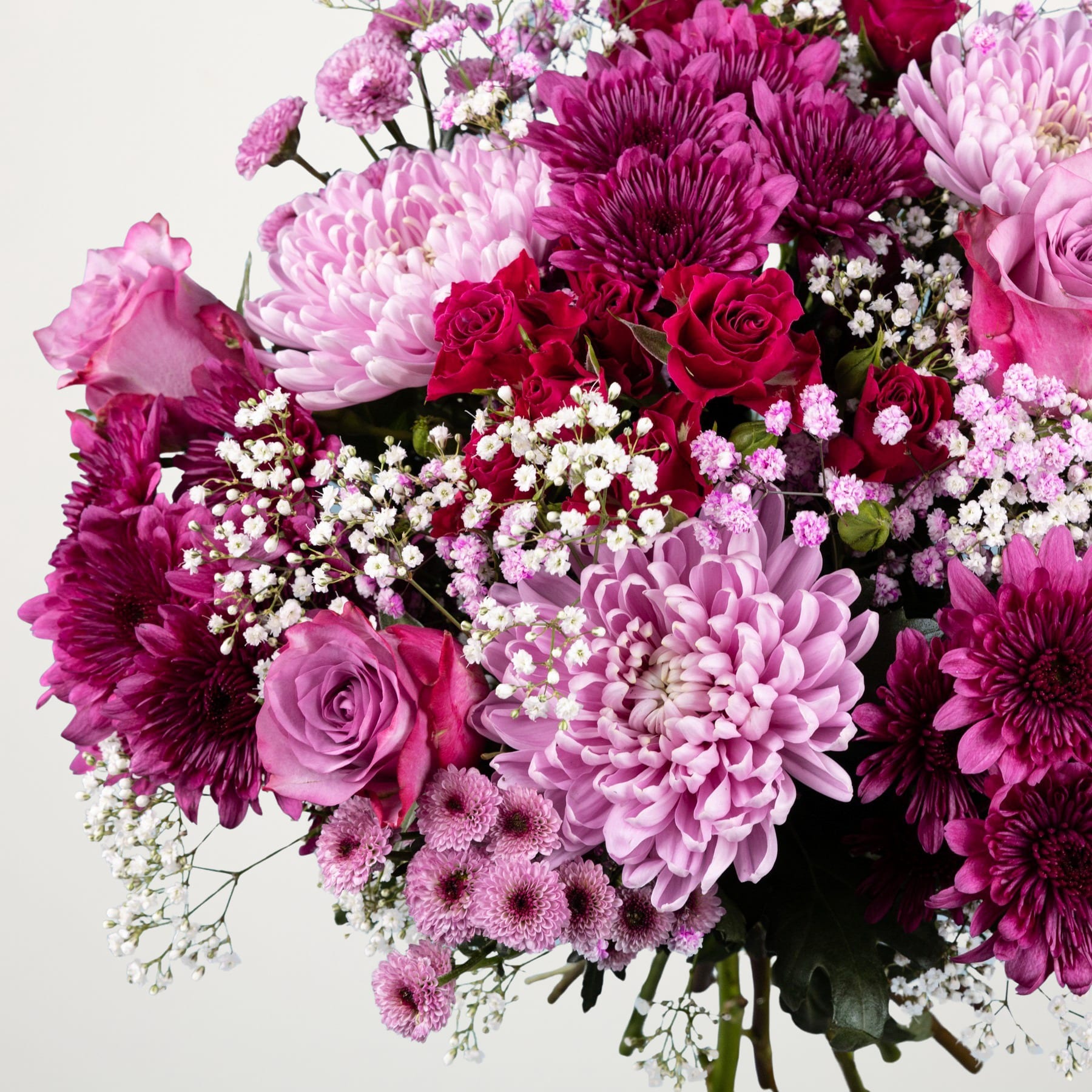 Ein farbenfroher Strauß aus Blumen in verschiedenen Rosa- und Lilatönen, darunter Rosen, Chrysanthemen und Schleierkraut, füllt den Rahmen vor einem schlichten weißen Hintergrund.