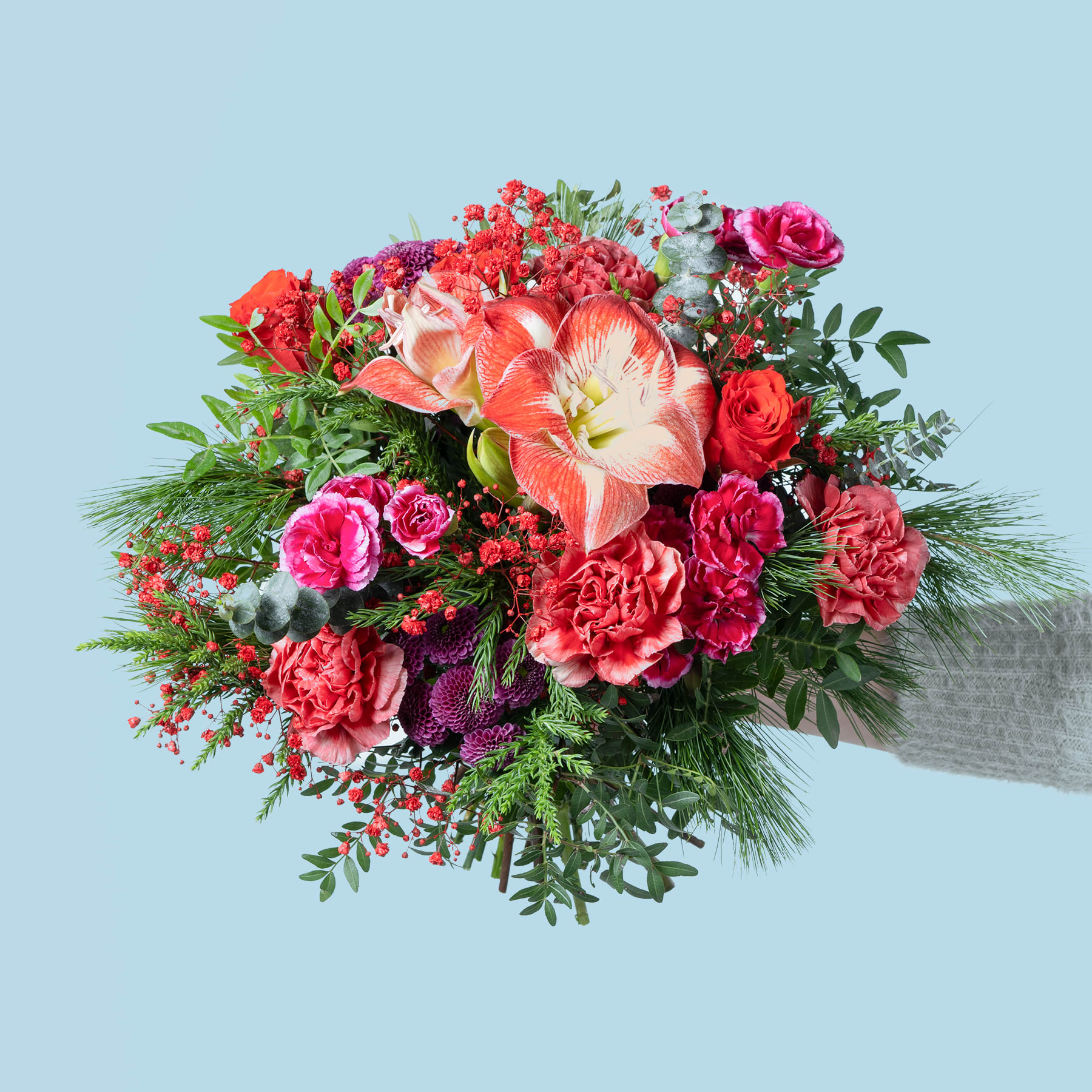 Ein leuchtender Strauß roter, rosa und orangefarbener Blumen, darunter Rosen, Nelken und andere Blüten, vor einem hellblauen Hintergrund.