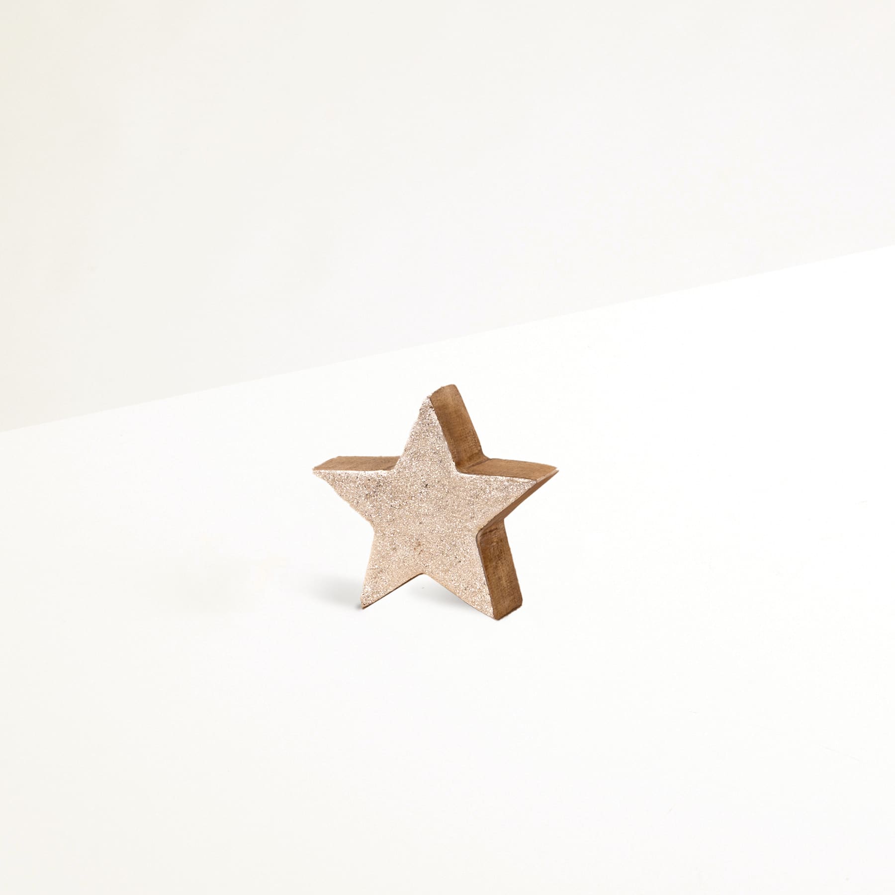 Ein einfaches, sternförmiges Holzobjekt befindet sich auf einem schlichten, weißen Hintergrund.