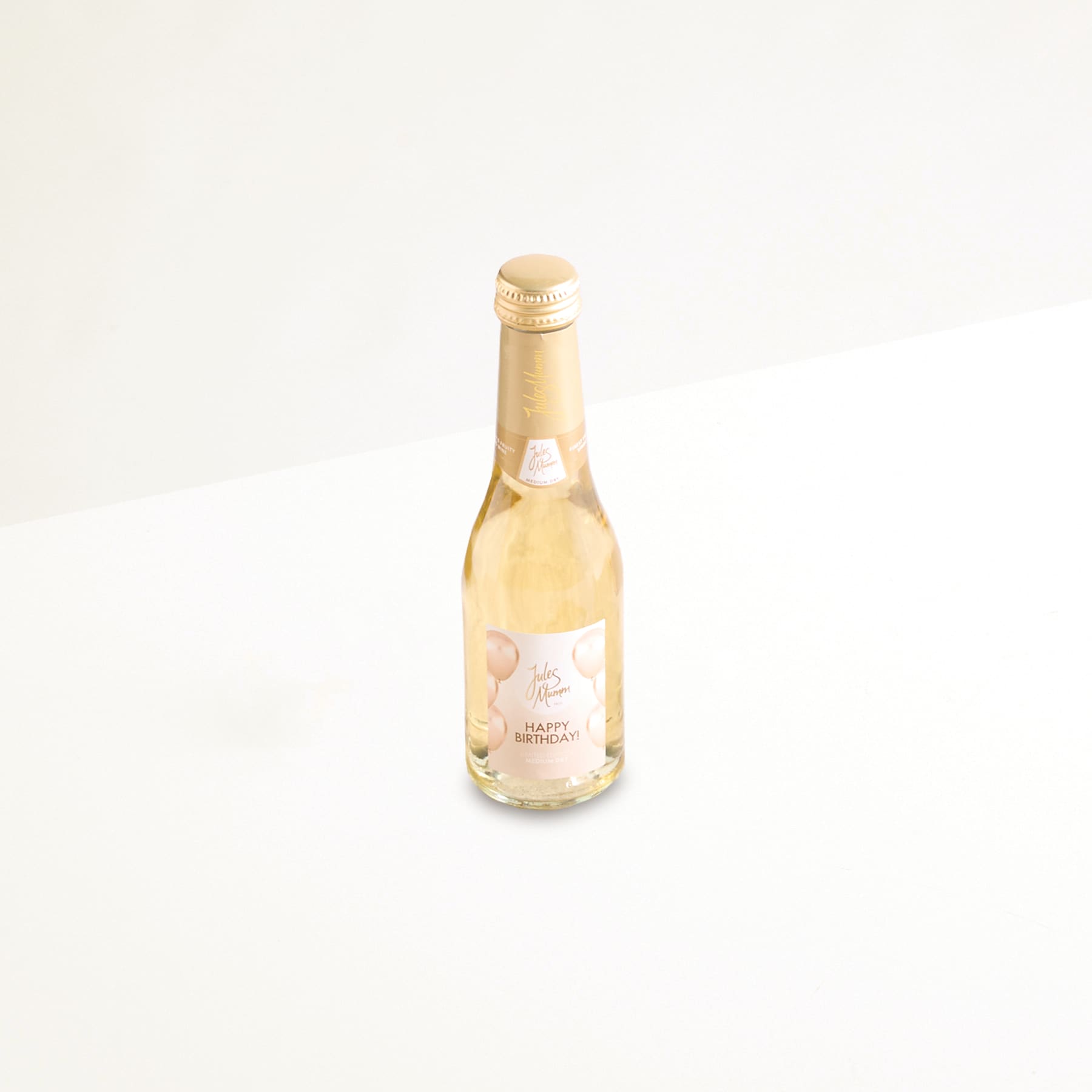 Eine einzelne Flasche Weißwein mit goldenem Etikett und Deckel steht auf einem schlichten weißen Hintergrund.