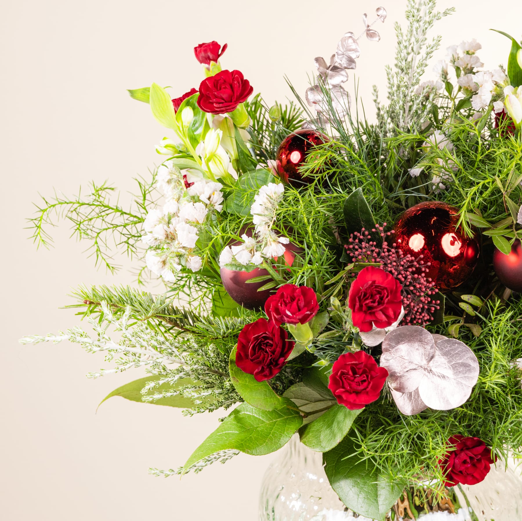 Ein lebendiger Strauß roter Rosen, weißer Blumen und üppigem Grün füllt den Rahmen und schafft ein optisch beeindruckendes und harmonisches Arrangement vor einem neutralen Hintergrund.