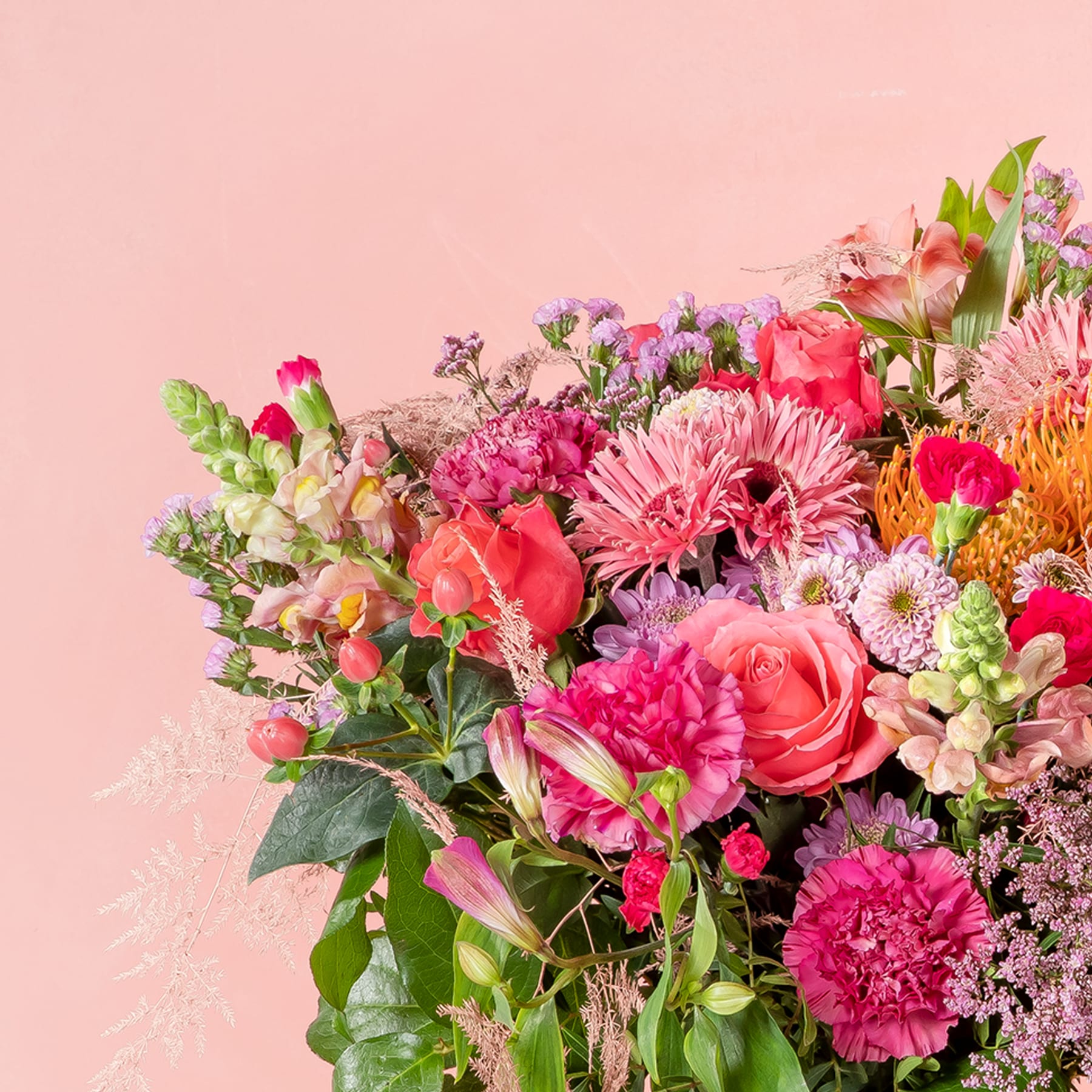 Ein lebendiger Strauß verschiedener rosa und roter Blumen, darunter Rosen, Nelken und Gänseblümchen, vor einem zartrosa Hintergrund.