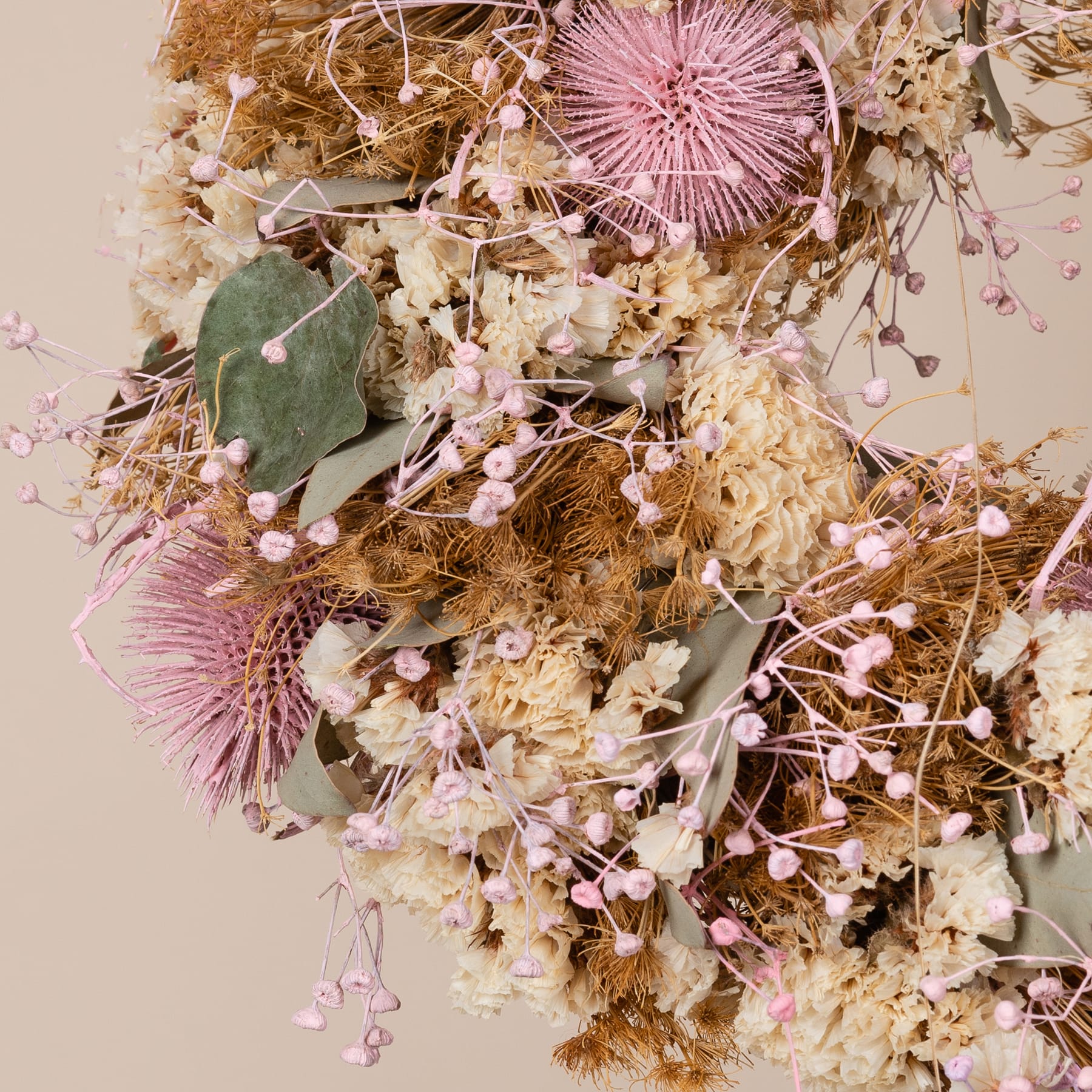 Auf einem Holztisch steht ein wunderschöner Kranz aus Trockenblumen. Seine leuchtenden Farben und das kunstvolle Arrangement schaffen eine warme und einladende Atmosphäre.